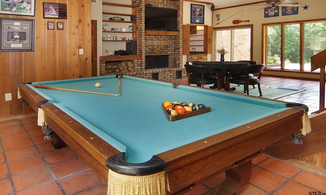 rec room with a brick fireplace, billiards, ceiling fan, and wood walls