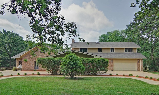 view of front of property with an attached garage, brick siding, concrete driveway, a front lawn, and a chimney