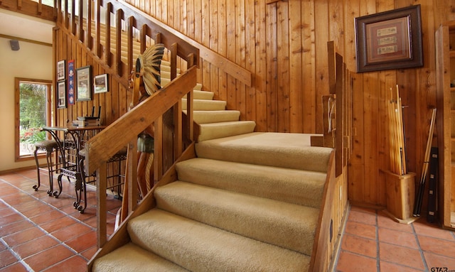 stairway with wood walls and tile patterned flooring