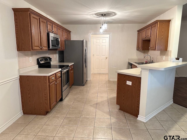 1521 Rice Rd Unit Z103, Tyler, TX 75703 - kitchen with appliances with stainless steel finishes, decorative backsplash, a sink, a peninsula, and light tile patterned floors