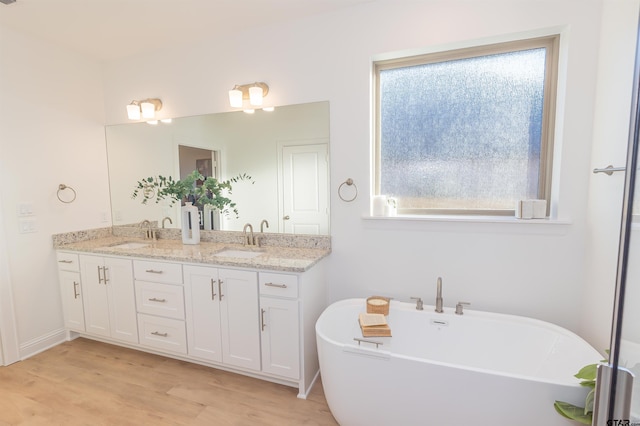 bathroom with hardwood / wood-style floors, vanity, and a tub