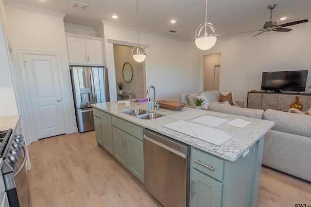 kitchen with light hardwood / wood-style floors, stainless steel appliances, hanging light fixtures, sink, and a kitchen island with sink