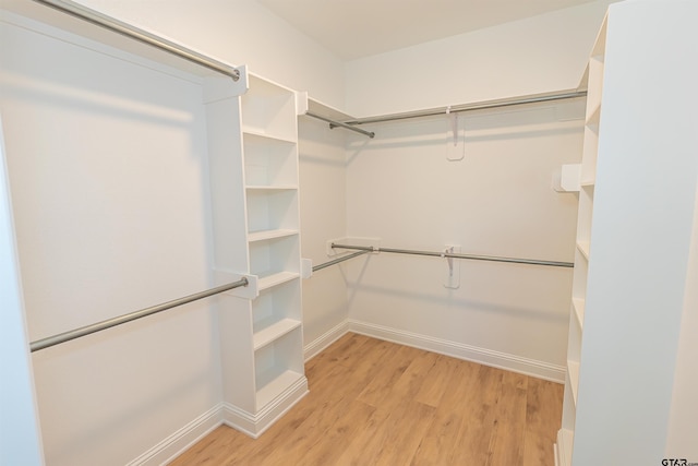 walk in closet with light hardwood / wood-style flooring