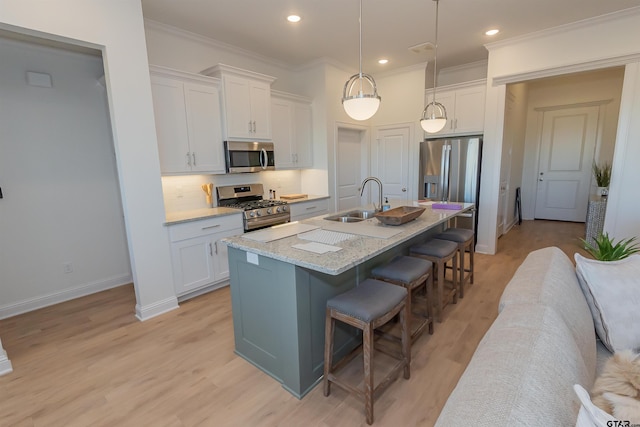 kitchen featuring appliances with stainless steel finishes, sink, white cabinets, a breakfast bar area, and a kitchen island with sink