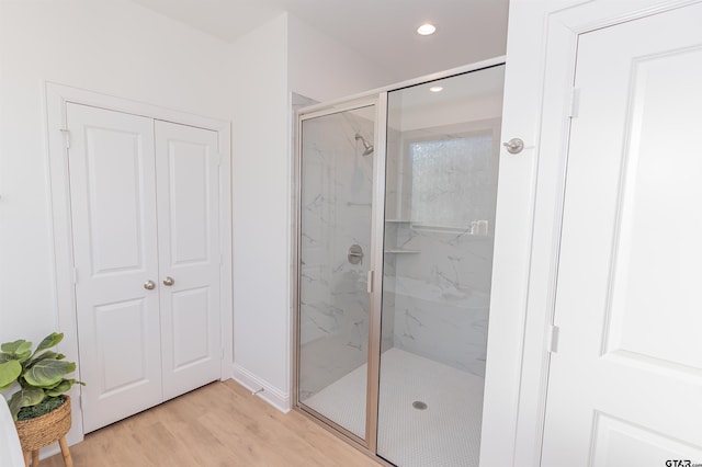 bathroom with wood-type flooring and a shower with door