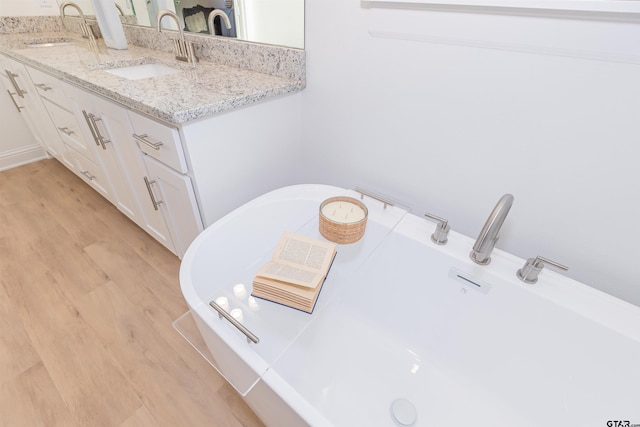 bathroom with a bathing tub, hardwood / wood-style floors, vanity, and washer / dryer