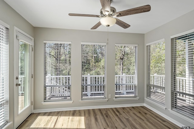 unfurnished sunroom featuring ceiling fan and a wealth of natural light