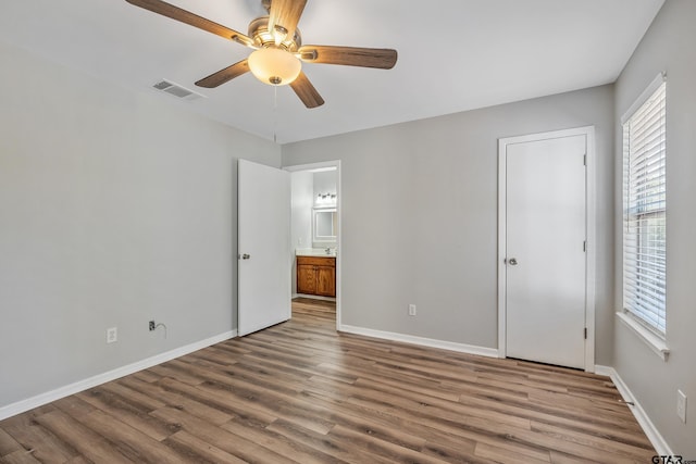 unfurnished bedroom featuring ceiling fan, wood finished floors, visible vents, and baseboards