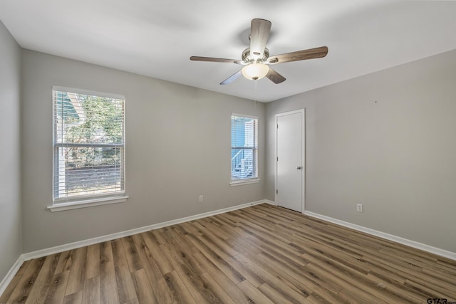 unfurnished room with baseboards, a wealth of natural light, and wood finished floors