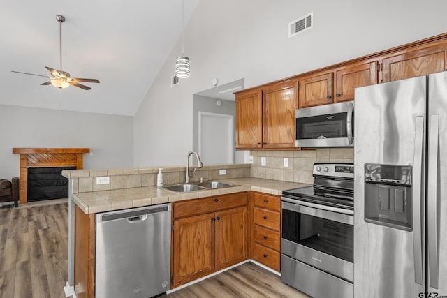 kitchen with stainless steel appliances, visible vents, open floor plan, a sink, and a peninsula