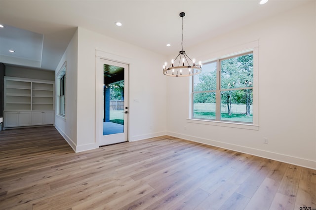unfurnished dining area with recessed lighting, baseboards, a chandelier, and wood finished floors