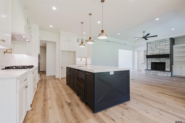 kitchen featuring a sink, premium range hood, gas cooktop, light countertops, and a ceiling fan