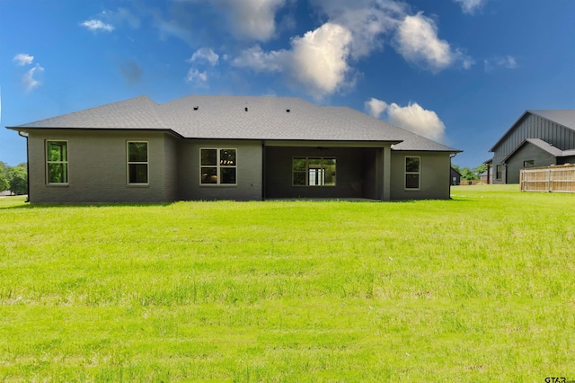 rear view of house featuring roof with shingles and a yard