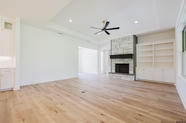 unfurnished living room with recessed lighting, ceiling fan, a tray ceiling, and light wood-type flooring