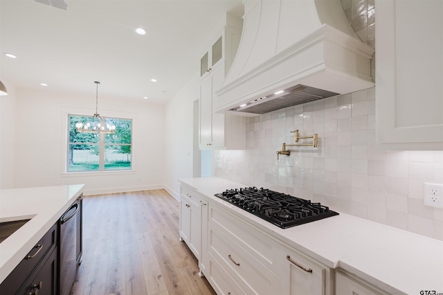 kitchen featuring light countertops, premium range hood, white cabinets, and black gas stovetop