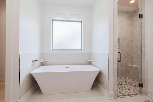 full bathroom featuring tile patterned floors, a soaking tub, tile walls, and a shower stall