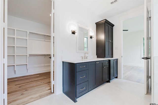 bathroom with visible vents, a walk in closet, wood finished floors, and vanity
