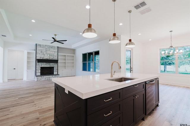 kitchen featuring a sink, light wood finished floors, ceiling fan with notable chandelier, and light countertops
