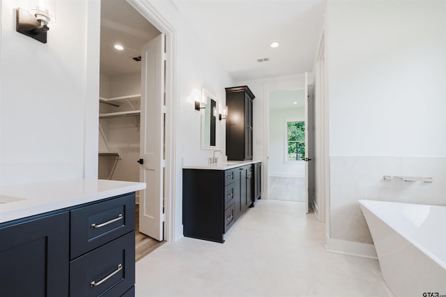 bathroom featuring vanity, a soaking tub, a spacious closet, and visible vents