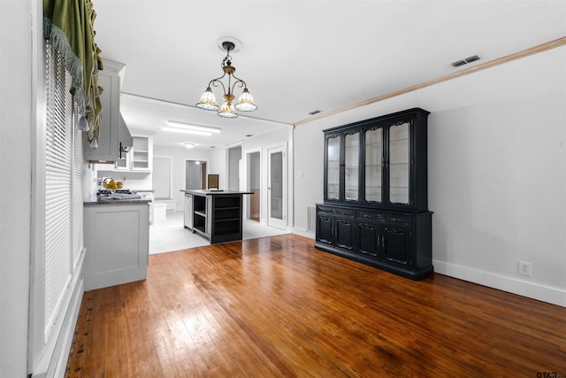 unfurnished living room with a chandelier, hardwood / wood-style flooring, and ornamental molding