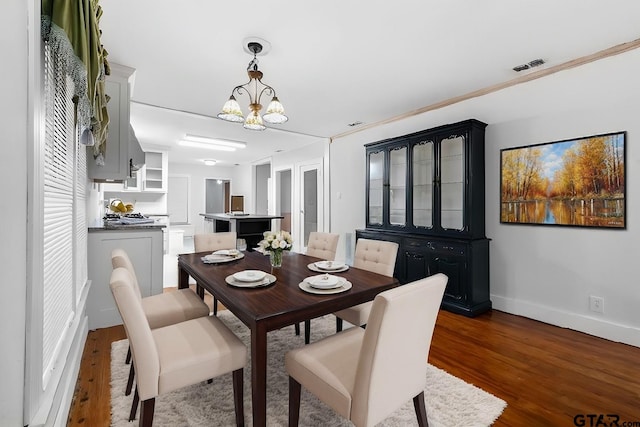 dining area with ornamental molding, dark hardwood / wood-style floors, and a notable chandelier