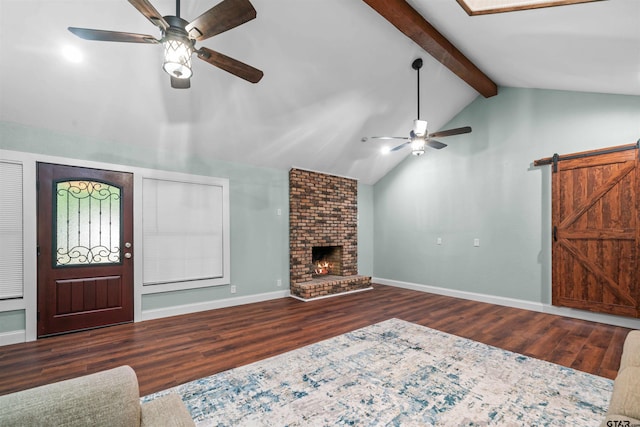 living room featuring ceiling fan, a barn door, vaulted ceiling with beams, dark hardwood / wood-style floors, and a fireplace