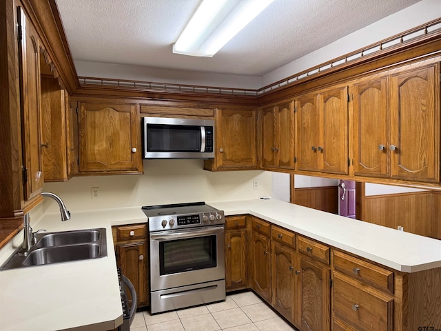 kitchen featuring stainless steel appliances, kitchen peninsula, a textured ceiling, sink, and light tile patterned flooring