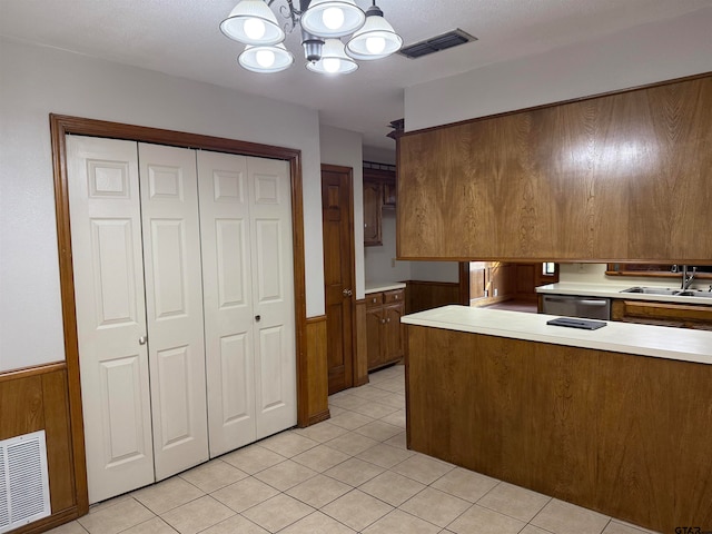 kitchen featuring stainless steel dishwasher, wooden walls, sink, and a chandelier