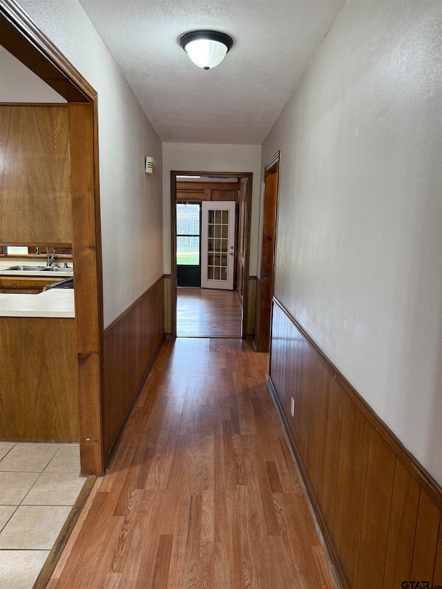 hall featuring hardwood / wood-style floors, a textured ceiling, wooden walls, and sink