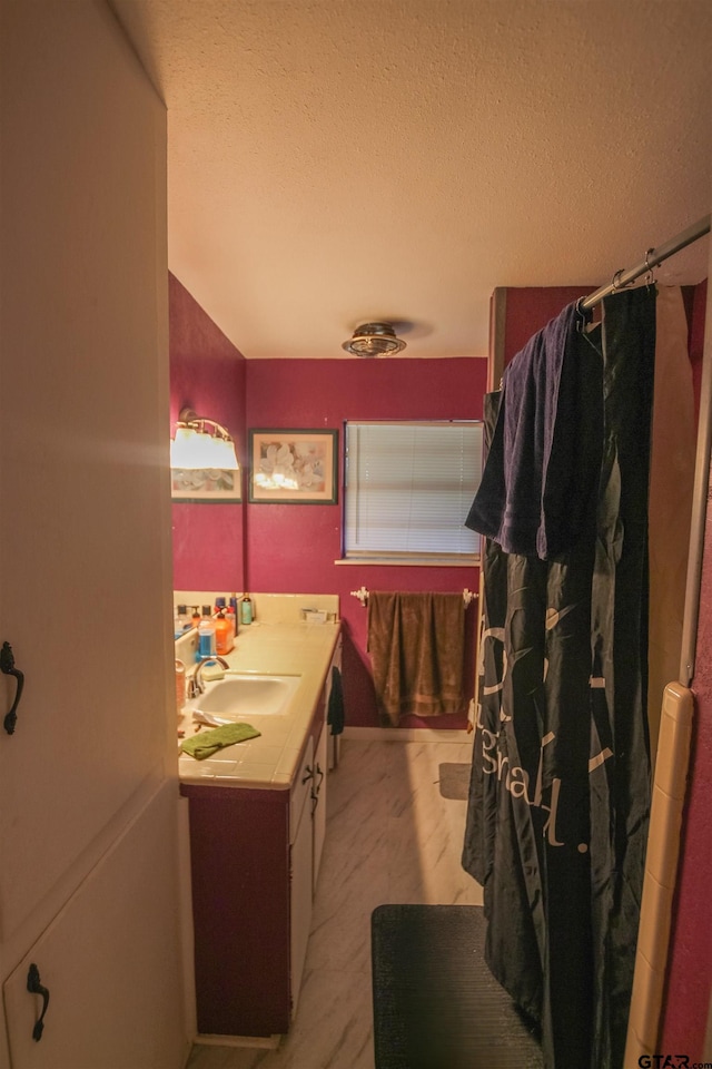 bathroom featuring vanity, a textured ceiling, and curtained shower