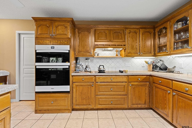 177 Paint Rock Pt, Holly Lake Ranch, TX 75765 - kitchen with light tile patterned floors, decorative backsplash, brown cabinetry, and double oven