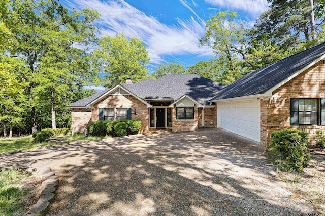177 Paint Rock Pt, Holly Lake Ranch, TX 75765 - view of front of home with roof with shingles, an attached garage, brick siding, aphalt driveway, and a chimney