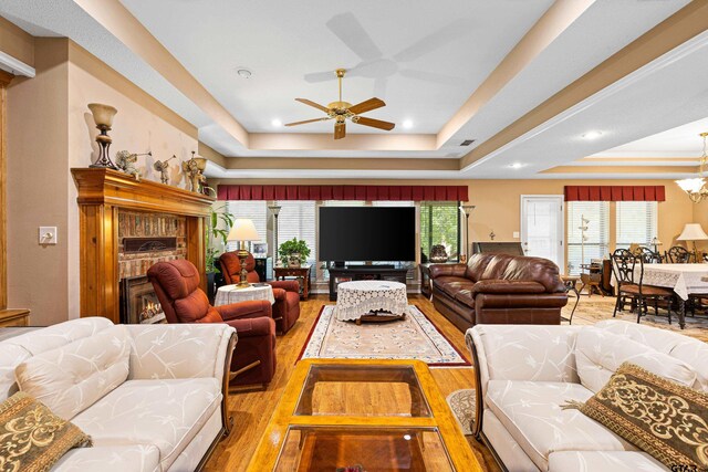 177 Paint Rock Pt, Holly Lake Ranch, TX 75765 - living room with a fireplace, light wood-style flooring, a raised ceiling, and ceiling fan with notable chandelier