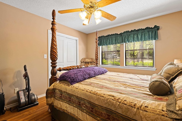 177 Paint Rock Pt, Holly Lake Ranch, TX 75765 - bedroom featuring a closet, baseboards, dark wood-style floors, a textured ceiling, and a ceiling fan