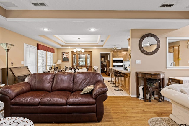 177 Paint Rock Pt, Holly Lake Ranch, TX 75765 - living area featuring visible vents, light wood-style flooring, a raised ceiling, and ceiling fan with notable chandelier