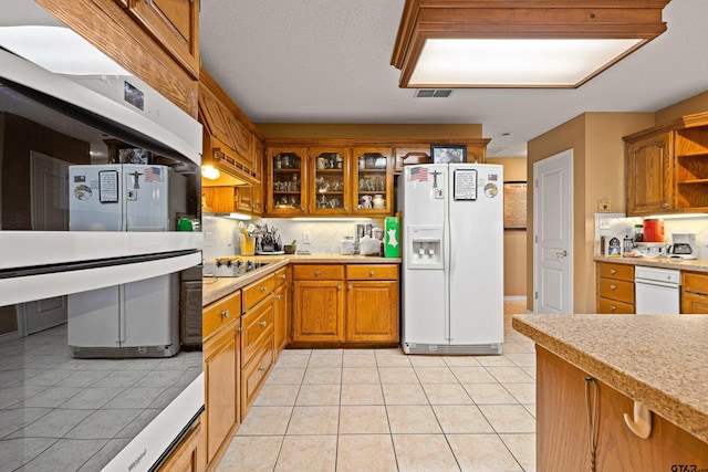 177 Paint Rock Pt, Holly Lake Ranch, TX 75765 - kitchen with white appliances, backsplash, brown cabinets, and light countertops
