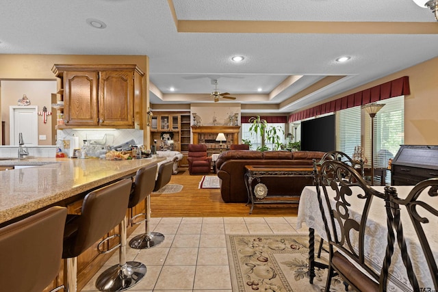 177 Paint Rock Pt, Holly Lake Ranch, TX 75765 - kitchen with plenty of natural light, a ceiling fan, a raised ceiling, and light tile patterned floors