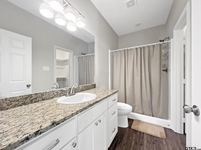 bathroom with wood-type flooring, a shower with shower curtain, vanity, and toilet