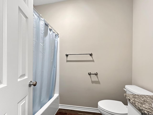 bathroom with hardwood / wood-style floors, shower / bath combo with shower curtain, and toilet