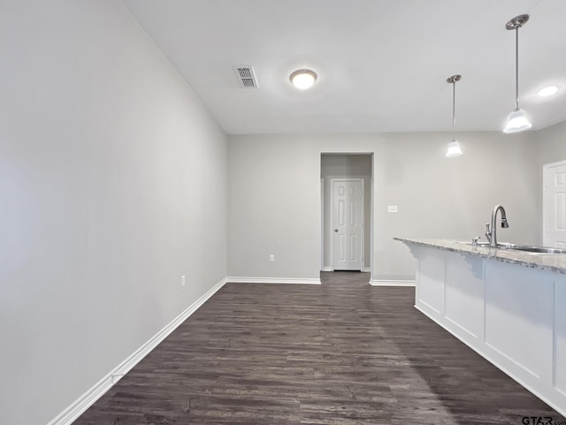 interior space with sink, white cabinetry, light stone counters, decorative light fixtures, and dark hardwood / wood-style floors