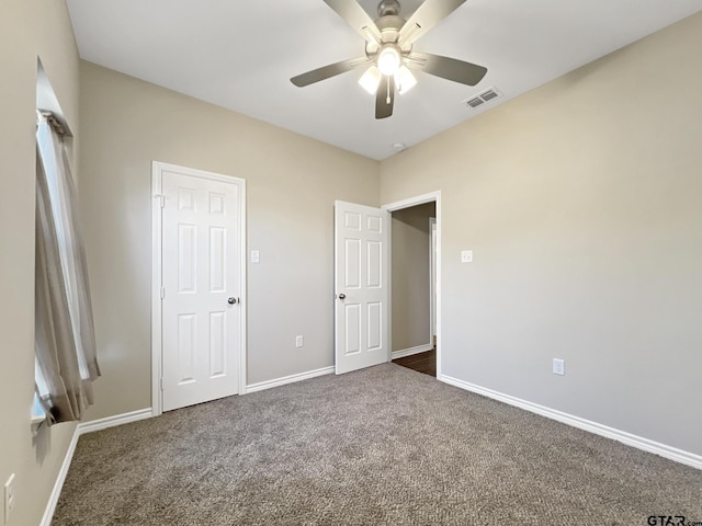 unfurnished bedroom featuring ceiling fan and dark carpet