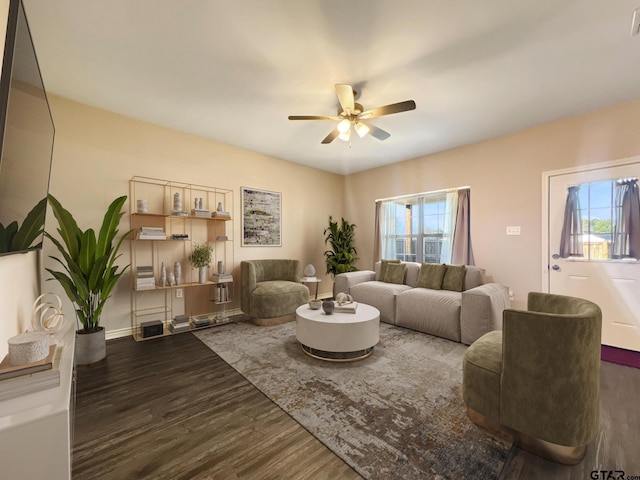 living room with dark wood-type flooring, ceiling fan, and plenty of natural light