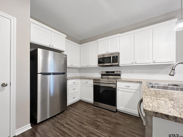 kitchen with appliances with stainless steel finishes, decorative light fixtures, sink, and white cabinets