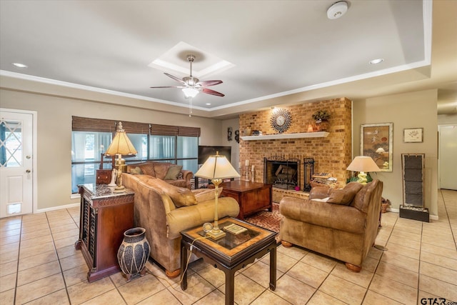 living room featuring ceiling fan, a tray ceiling, light tile patterned flooring, and a fireplace