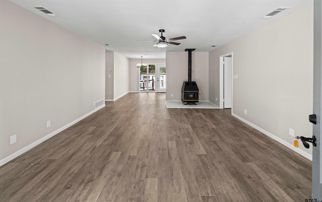 unfurnished living room with dark wood-type flooring, ceiling fan, and a wood stove