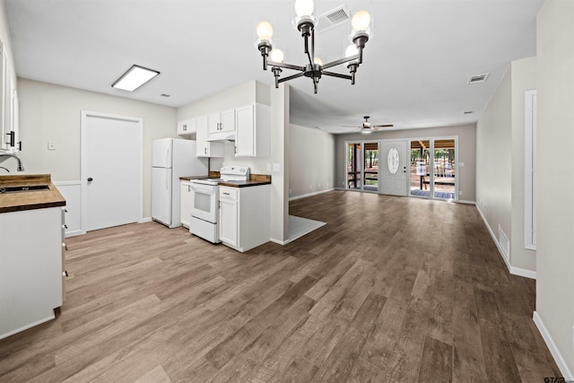 kitchen with ceiling fan with notable chandelier, hardwood / wood-style floors, sink, white cabinetry, and white appliances