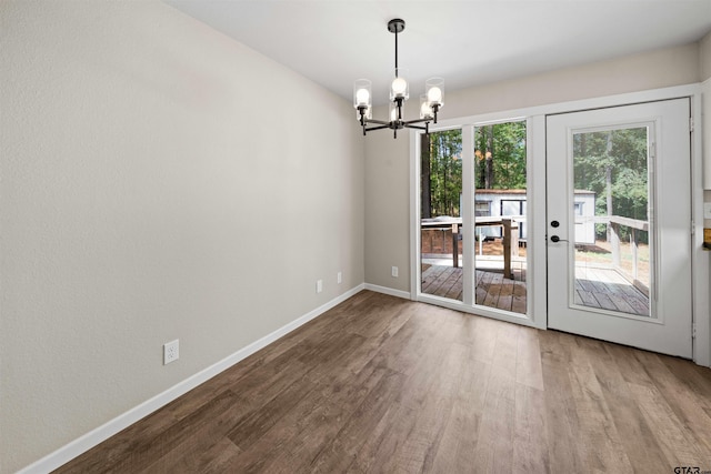 unfurnished dining area with hardwood / wood-style flooring, an inviting chandelier, and french doors