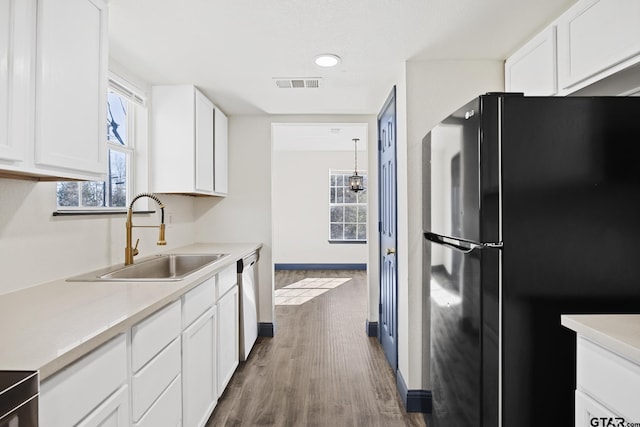 kitchen featuring light countertops, visible vents, freestanding refrigerator, a sink, and dishwasher