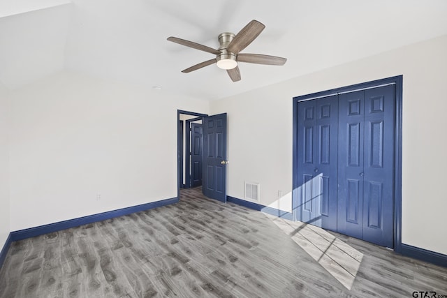 unfurnished bedroom with a closet, visible vents, ceiling fan, wood finished floors, and baseboards