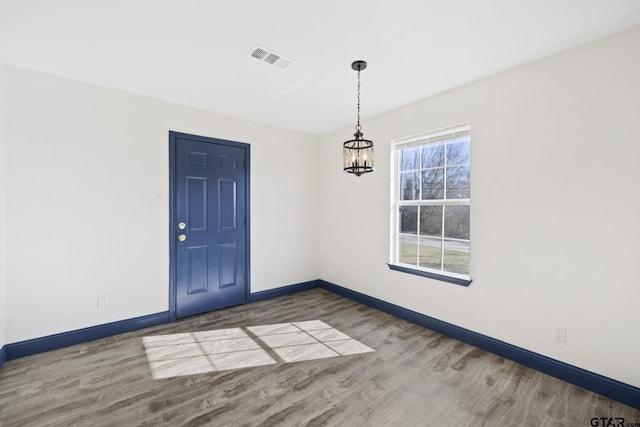 interior space featuring a chandelier, visible vents, baseboards, and wood finished floors